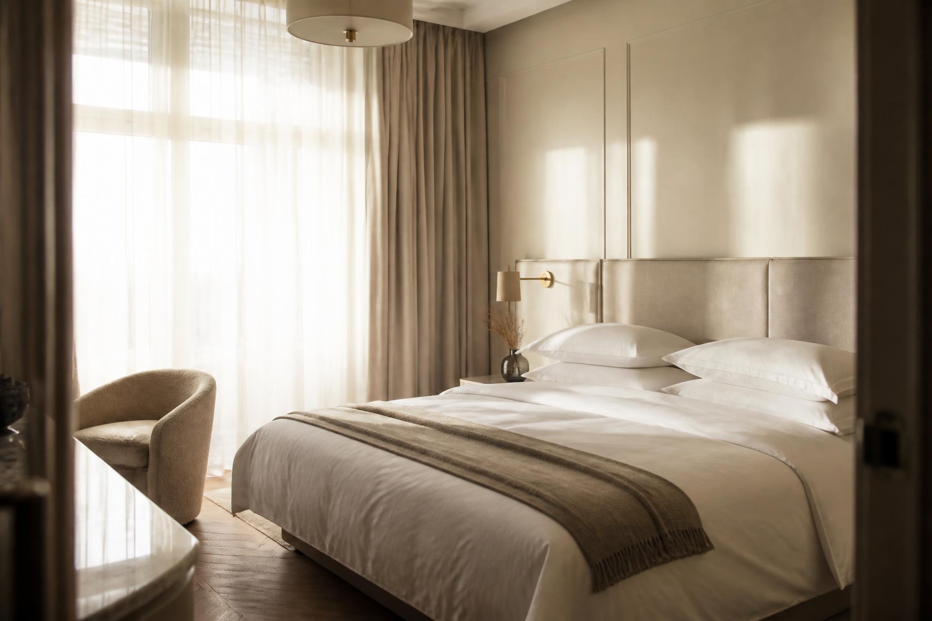 Beautifully made king bed with pressed white linen in a light-filled London flat